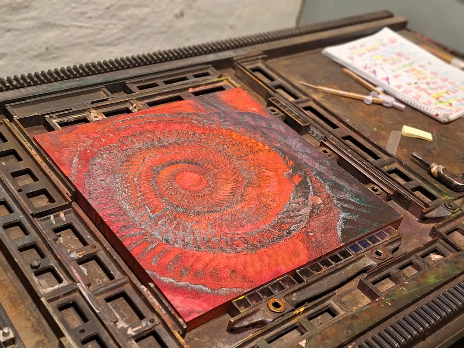 The inked woodblock with the ammonite spiral in the bed of the letterpress