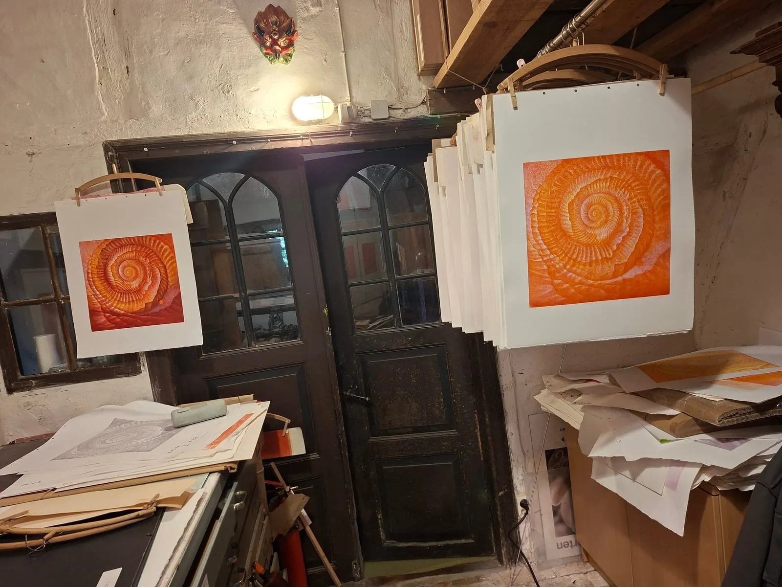 Two finished prints in the print workshop beside an old dark door