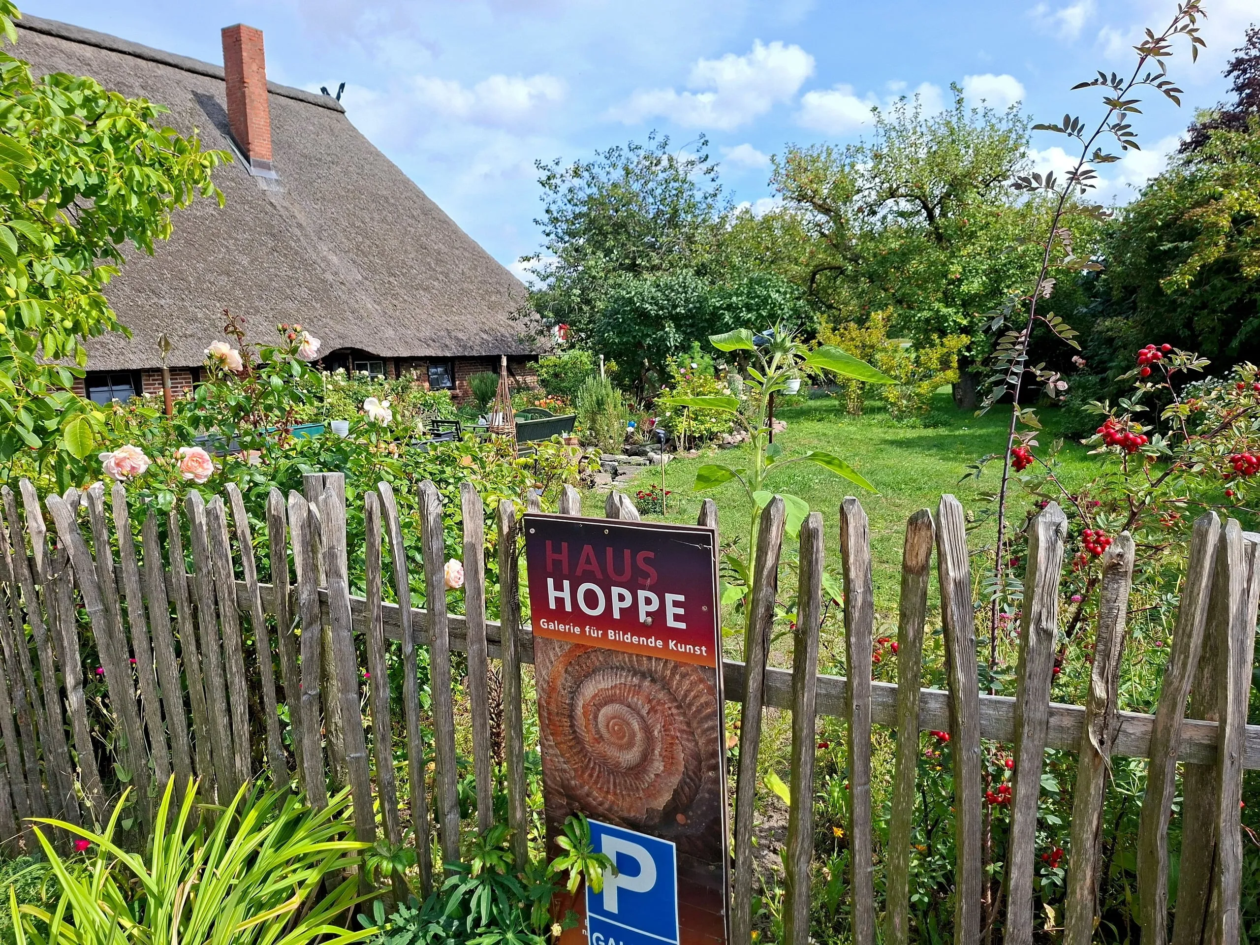 Roses and perennials in the cottage garden, with the sign of the HAUS HOPPE gallery