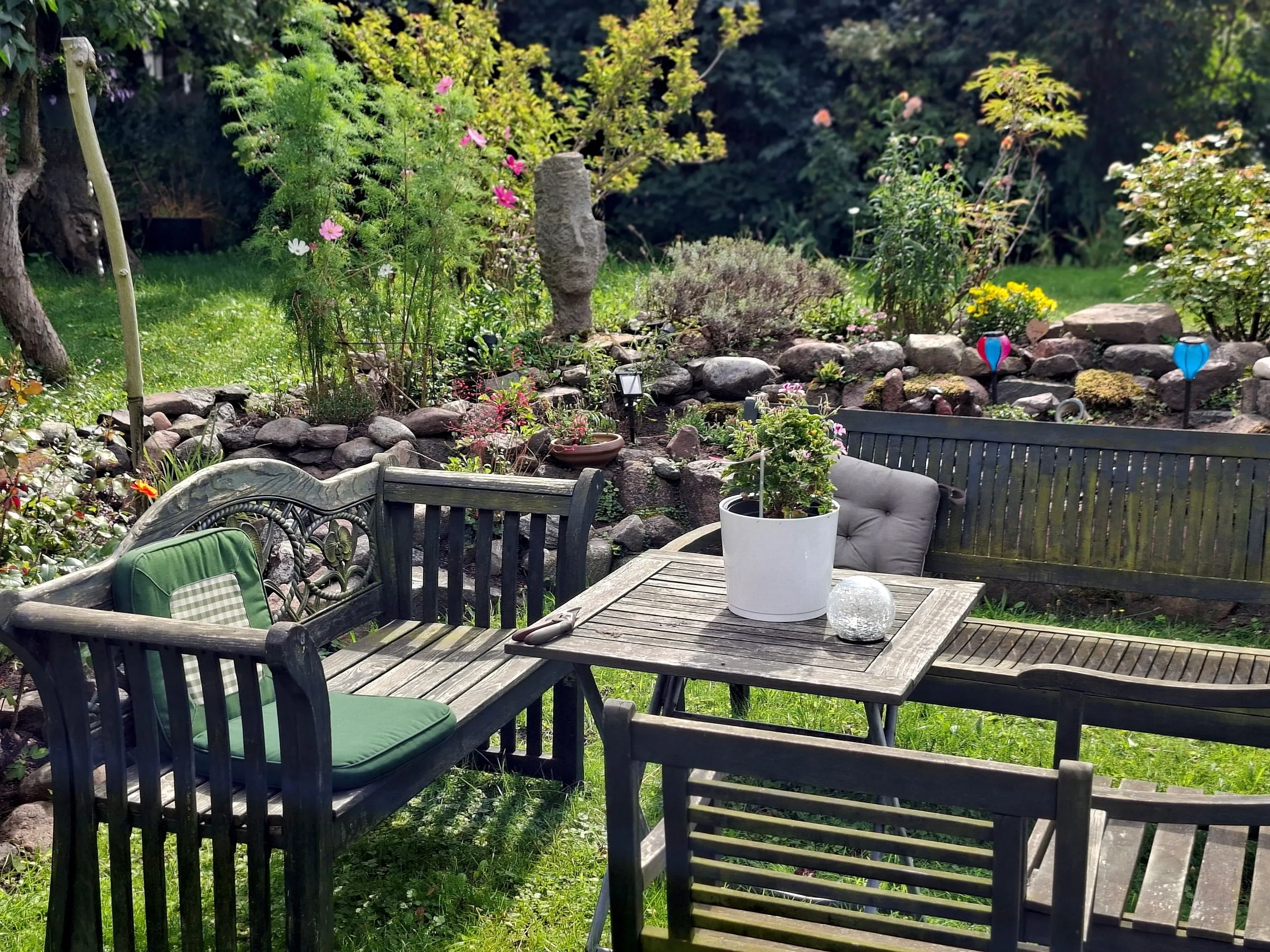 Quiet seating corner in the garden with bench, table and a small rockery