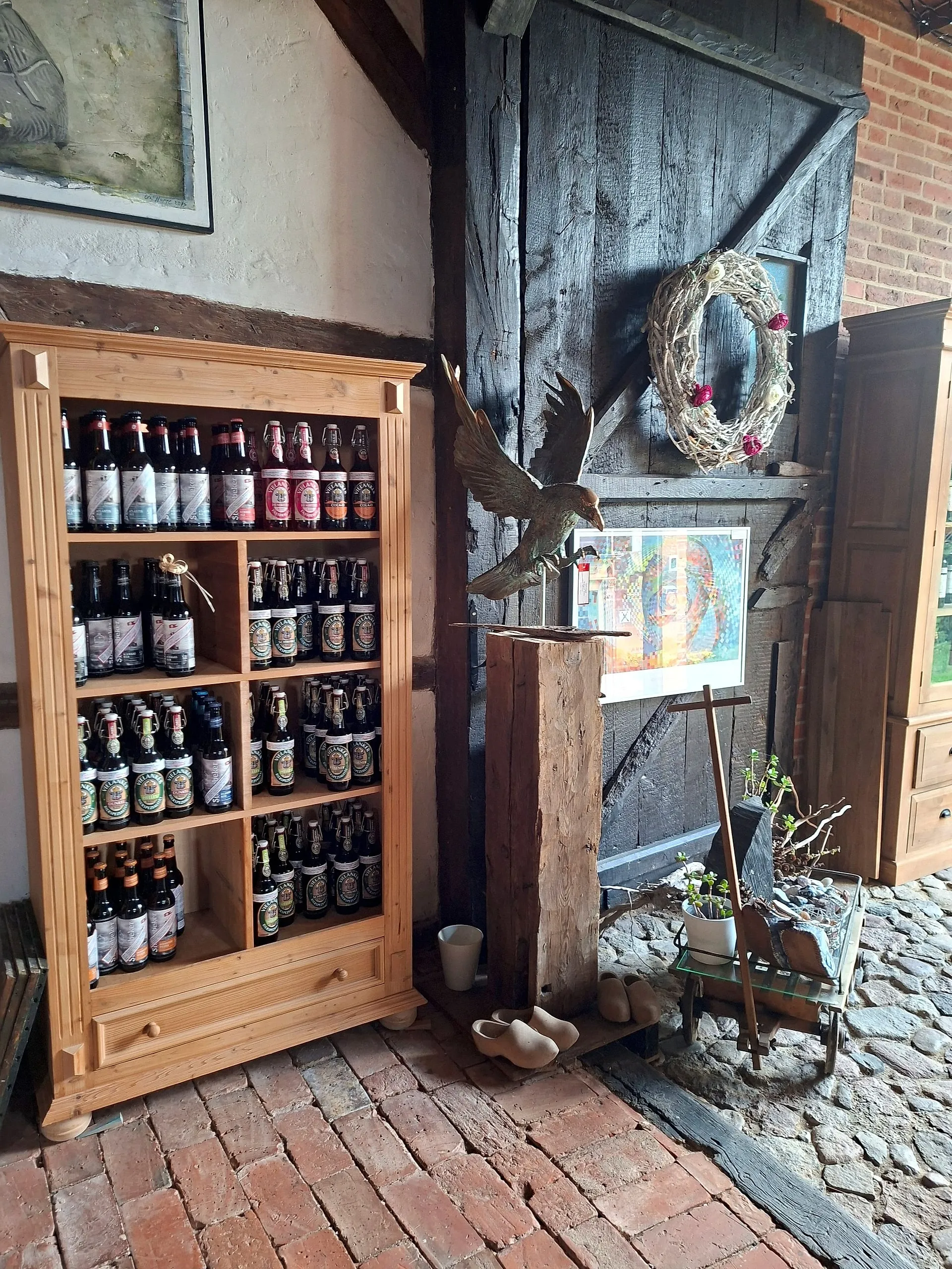 Bottle cabinet in the farm shop beside an eagle sculpture at the old barn door