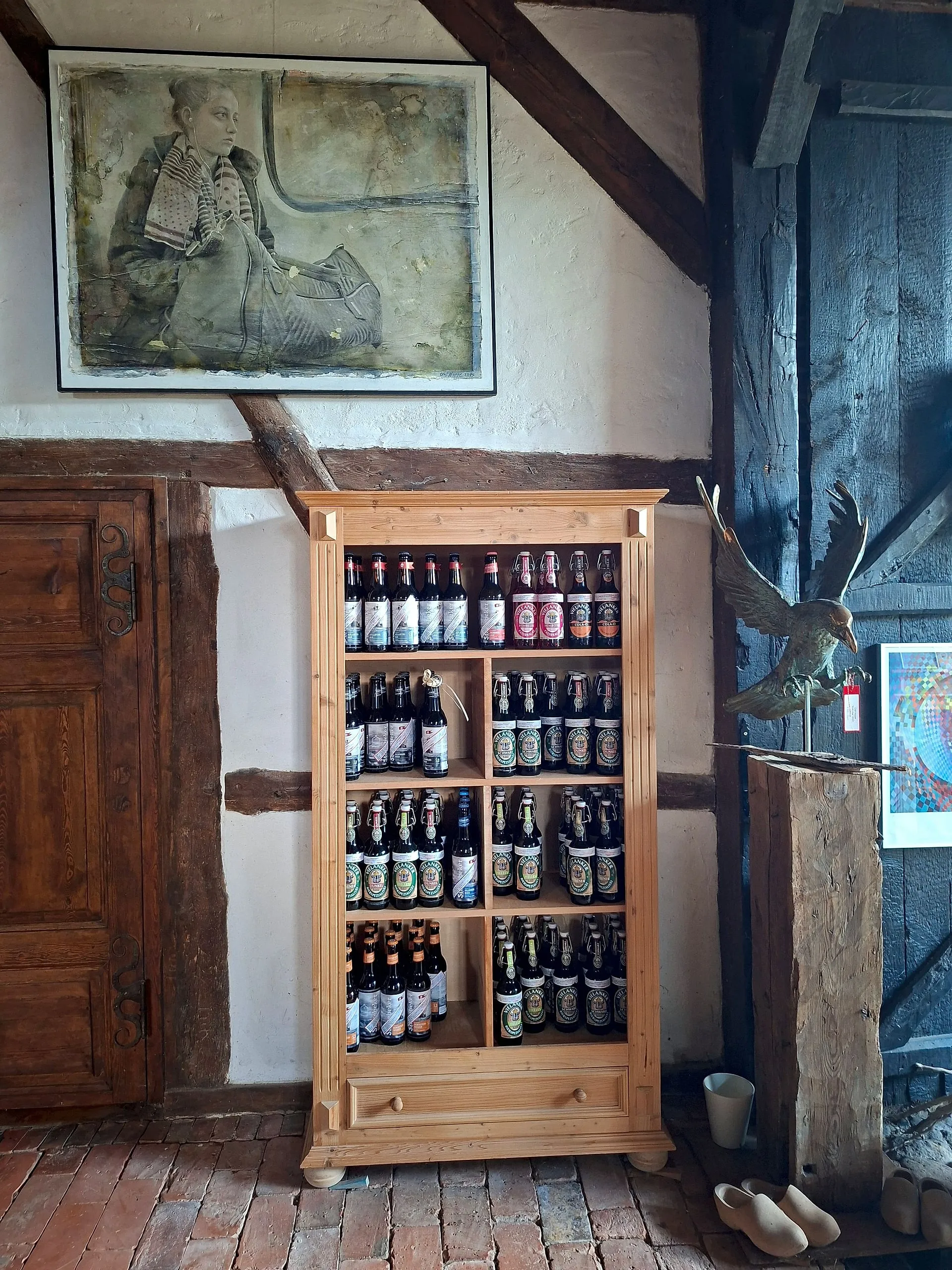 Wooden cabinet full of beer bottles, including editions with art labels