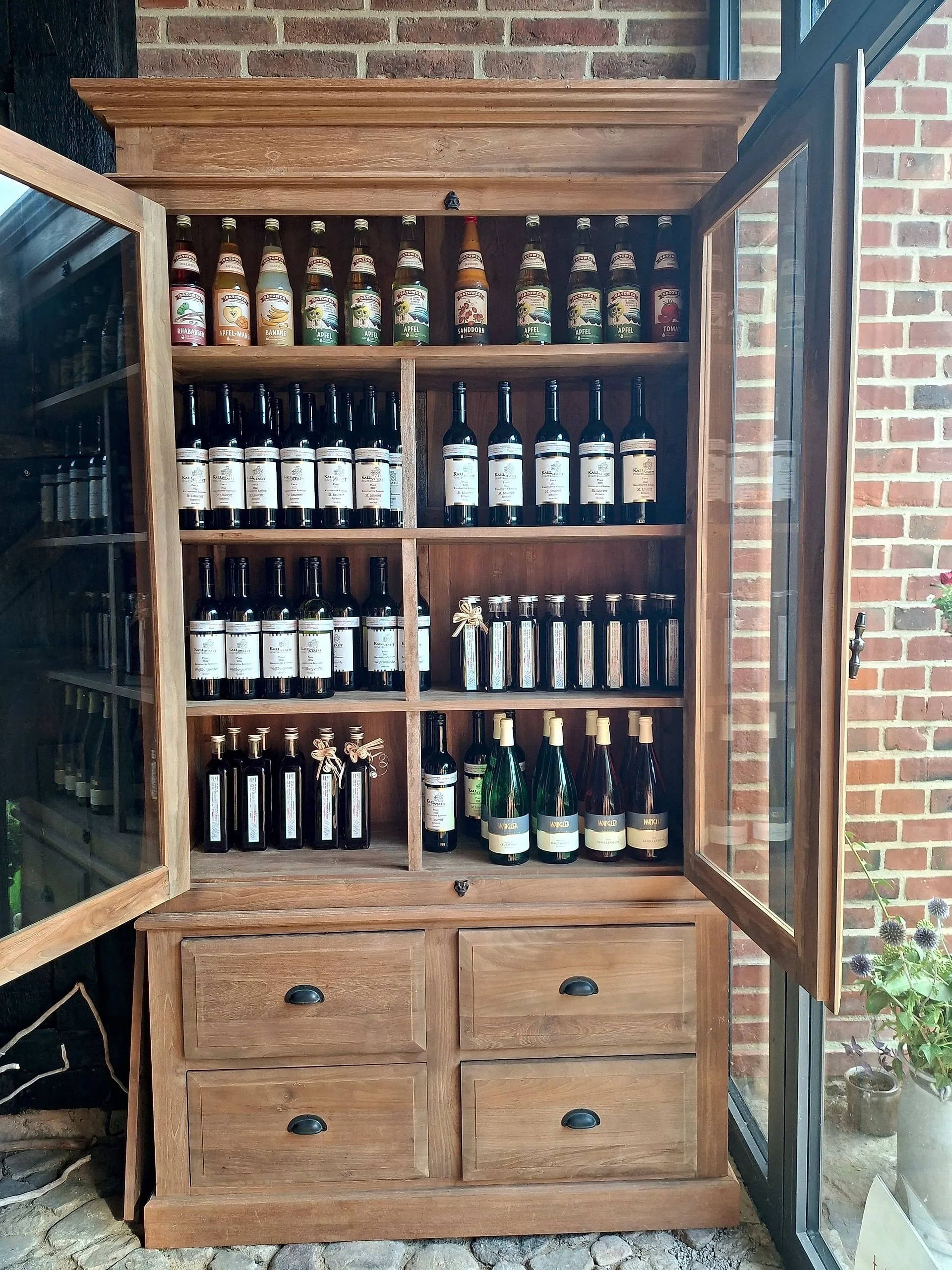Glazed oak cabinet with regional juices, red wines and small bottles of oil and vinegar