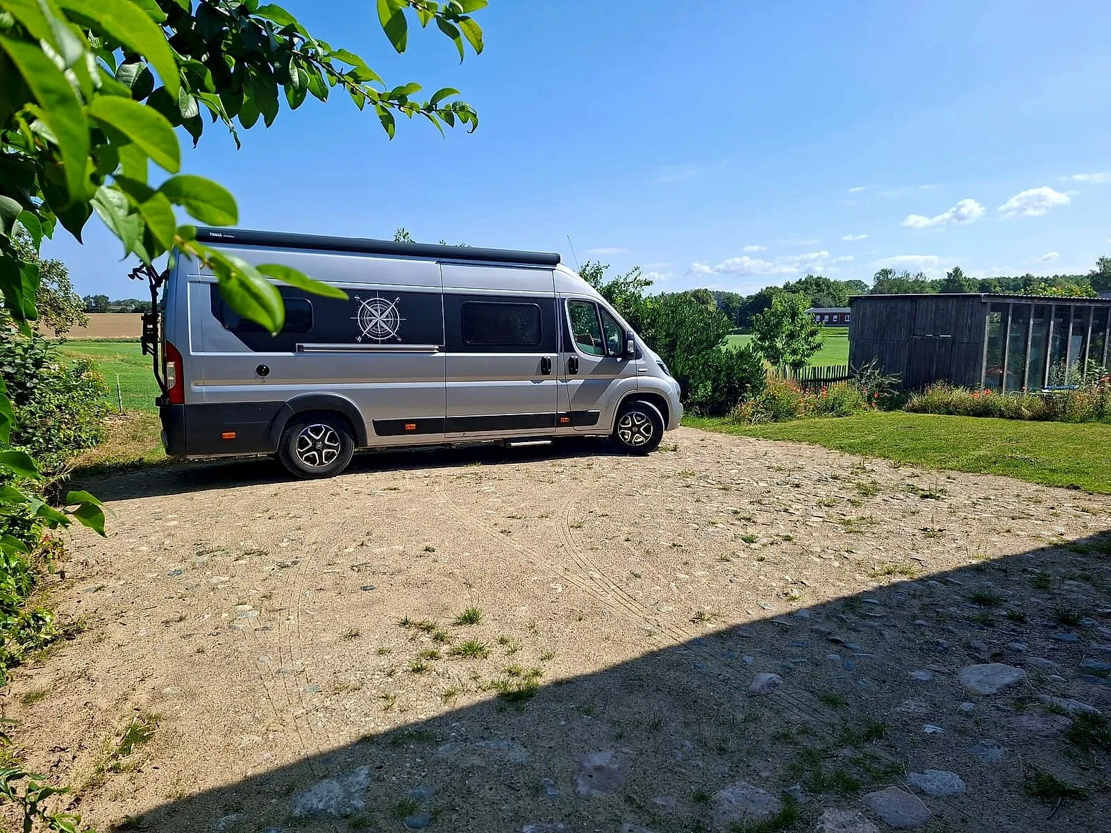 Motorhome on the pitch with trees and open countryside behind